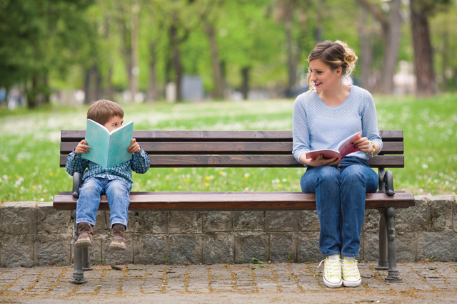 mother and child reading books on bench in the park